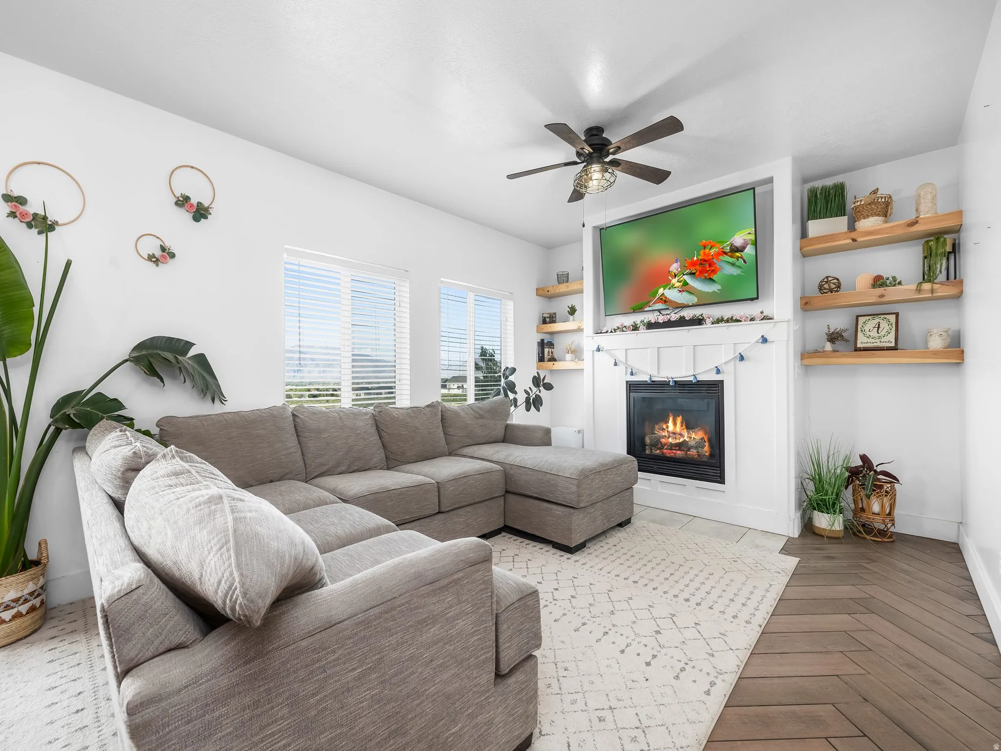 Living room with parquet floors, ceiling fan, and a glass covered fireplace