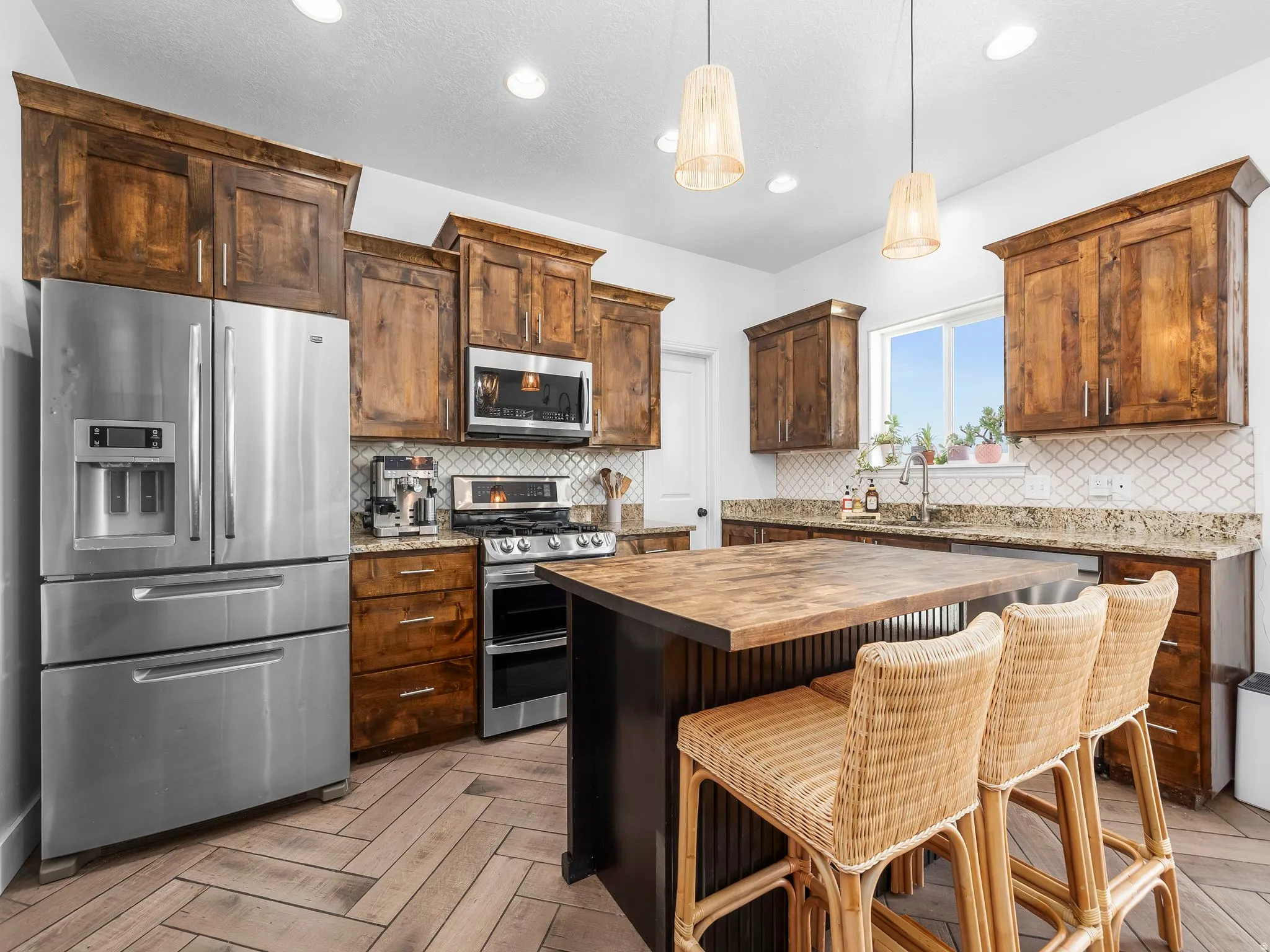 Kitchen featuring wood counters, stainless steel appliances, a kitchen breakfast bar, light wood finished floors, and a center island