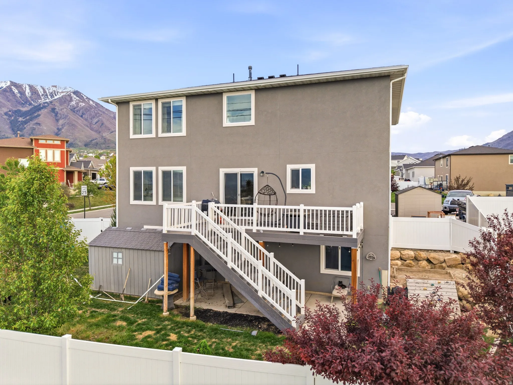 Back of house with a fenced backyard, a deck with mountain view, stucco siding, a residential view, and a patio
