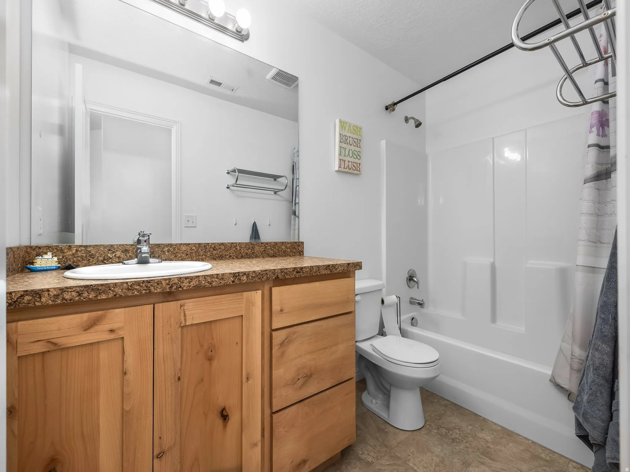 Bathroom with vanity, shower / tub combo, and a textured ceiling