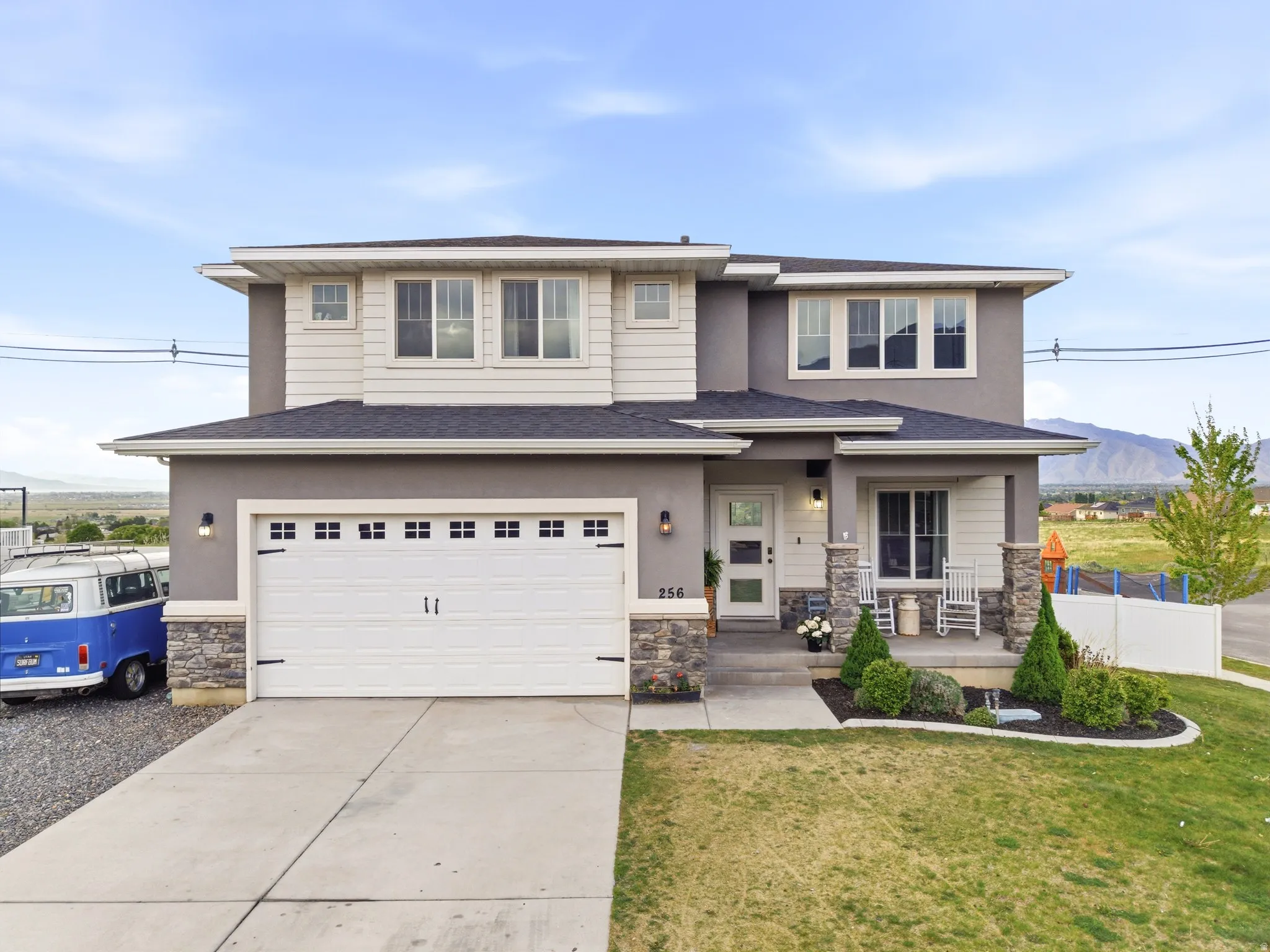 Prairie-style home featuring stone siding, covered porch, a mountain view, concrete driveway, and an attached garage