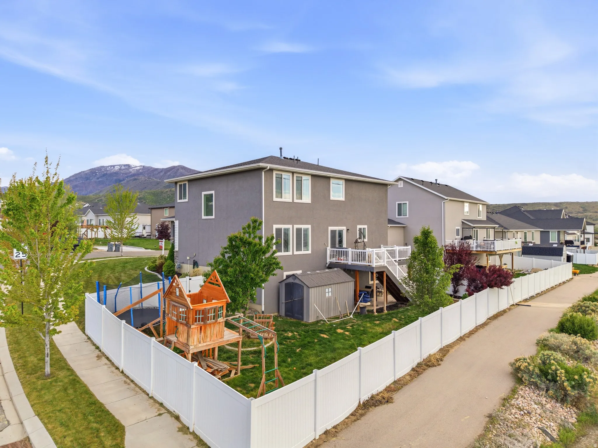 View of front of property with stucco siding, a residential view, a deck with mountain view, and an outdoor structure