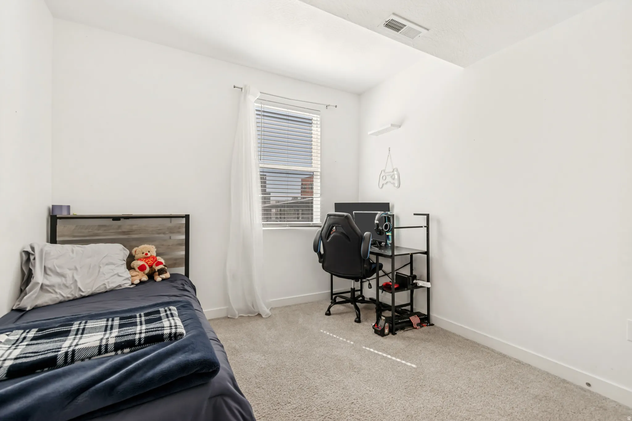 Bedroom featuring light colored carpet and a desk