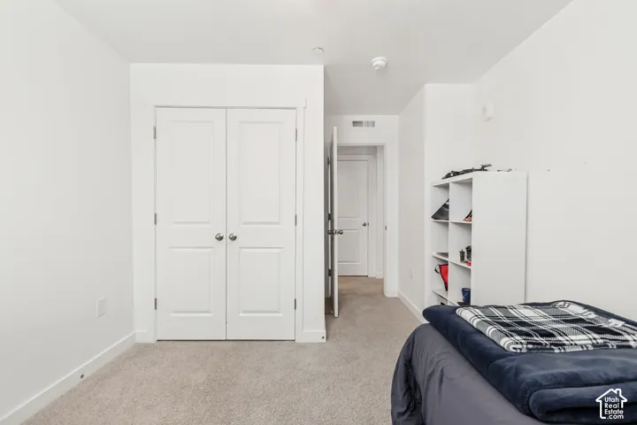 Bedroom with light carpet and a closet