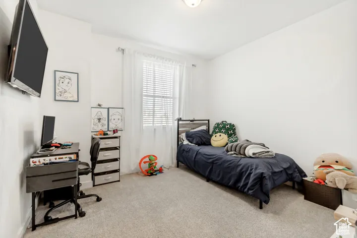 Bedroom with light colored carpet and an office area