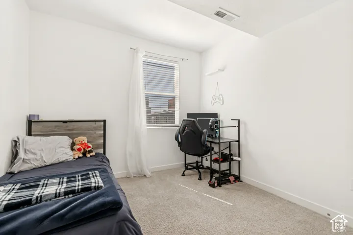 Bedroom featuring light colored carpet and a desk