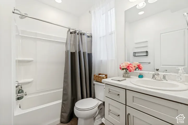 Full bathroom featuring vanity, shower / bathtub combination with curtain, and recessed lighting