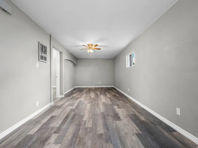 Empty room featuring arched walkways, dark wood-type flooring, and a ceiling fan