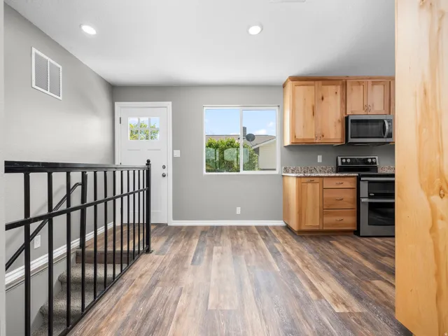 Kitchen featuring stainless steel appliances, dark wood-type flooring, recessed lighting, light wood finish cabinets, and light stone countertops