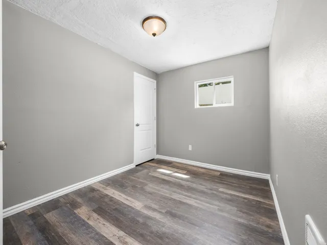 Spare room with a textured wall, dark wood-style floors, and a textured ceiling