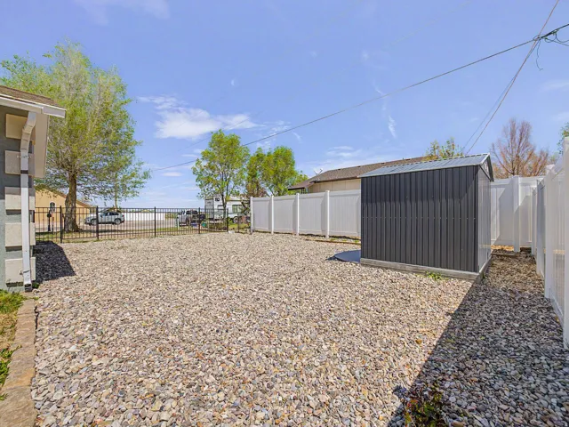 Fenced backyard featuring a storage unit
