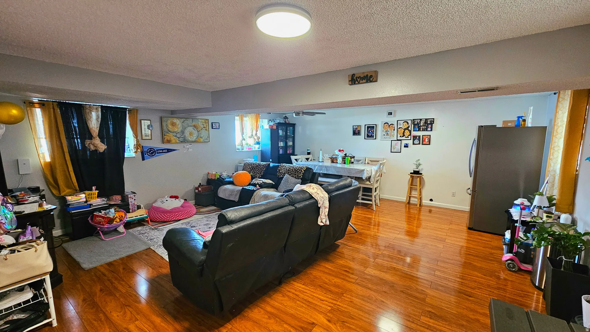 Living room with wood-type flooring, a textured ceiling, and a ceiling fan