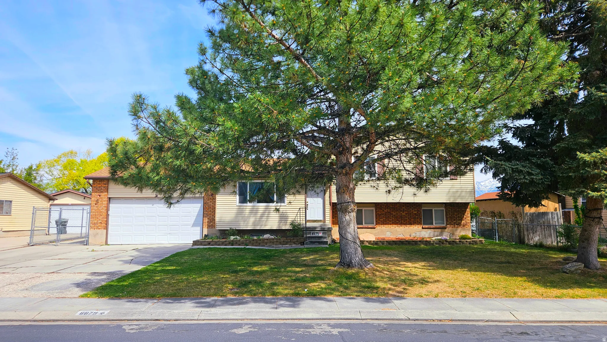 Split level home with driveway, a garage, and brick siding