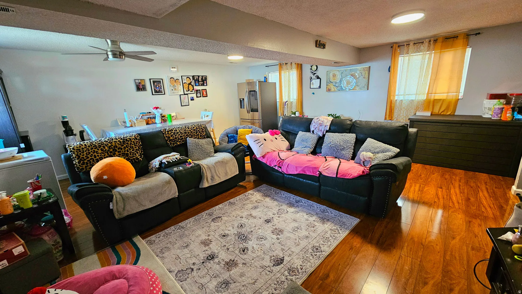 Living area with hardwood / wood-style flooring, a textured ceiling, and a ceiling fan