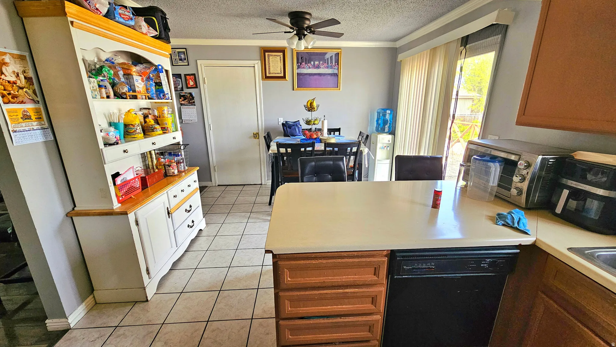 Kitchen featuring a peninsula, light countertops, ceiling fan, dishwasher, and ornamental molding