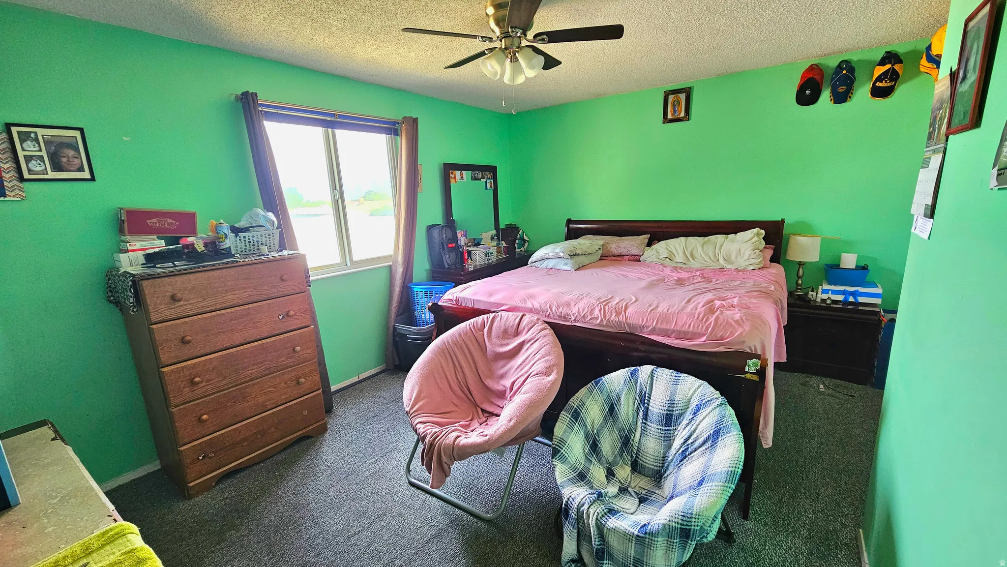 Bedroom with dark carpet, ceiling fan, and a textured ceiling