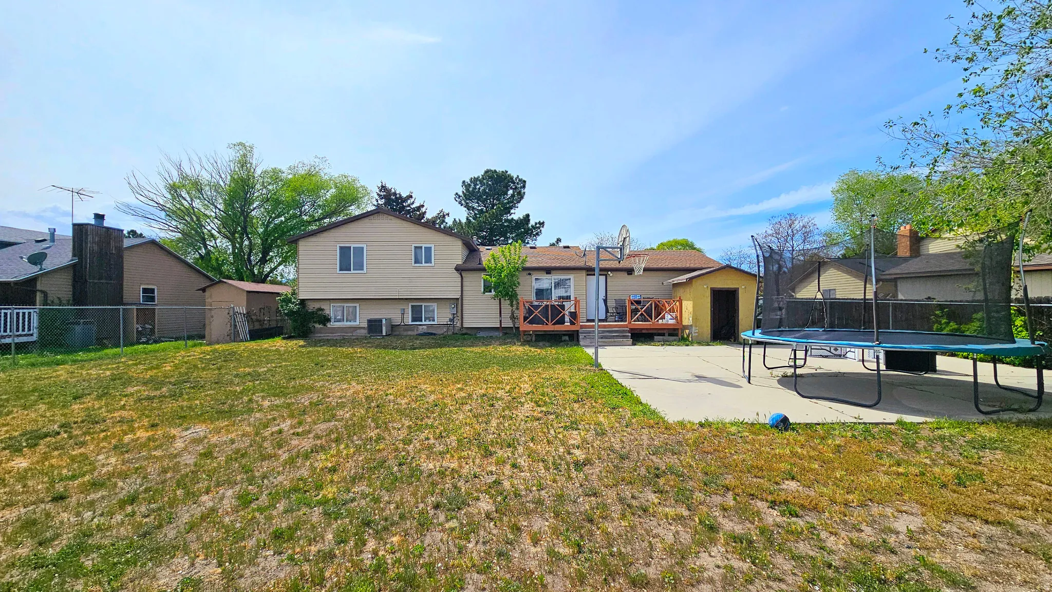 Rear view of property featuring a trampoline, a deck, and a fenced backyard