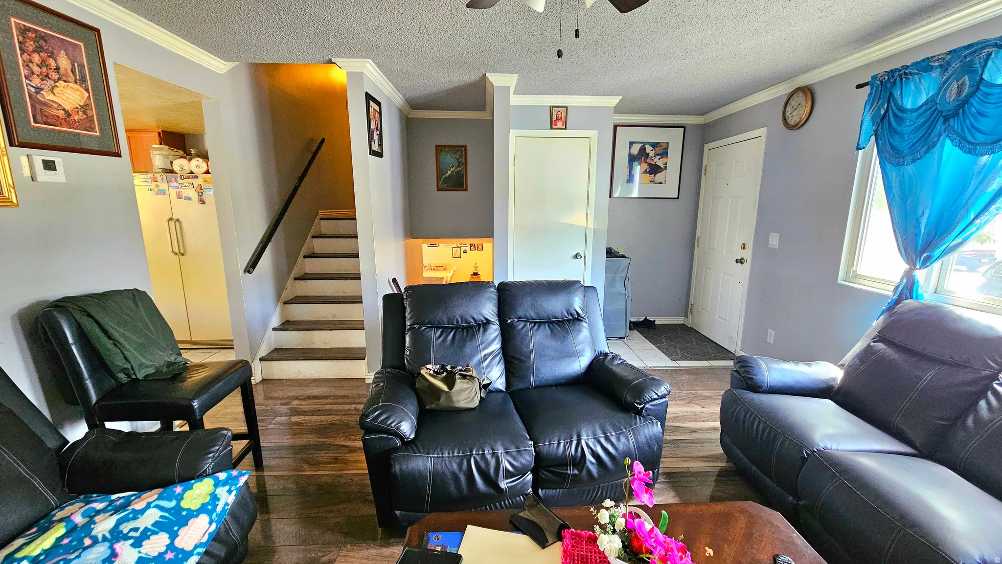 Living area featuring wood finished floors, ornamental molding, a textured ceiling, and ceiling fan