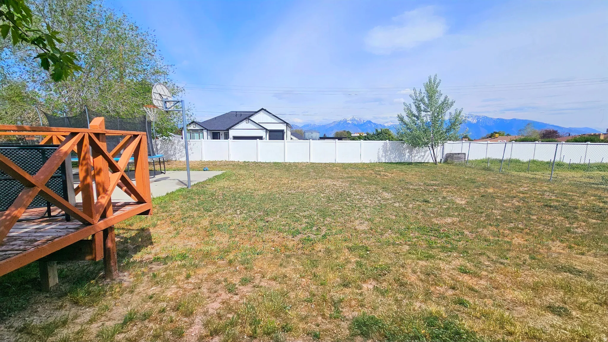 Fenced backyard featuring a trampoline and a mountain view