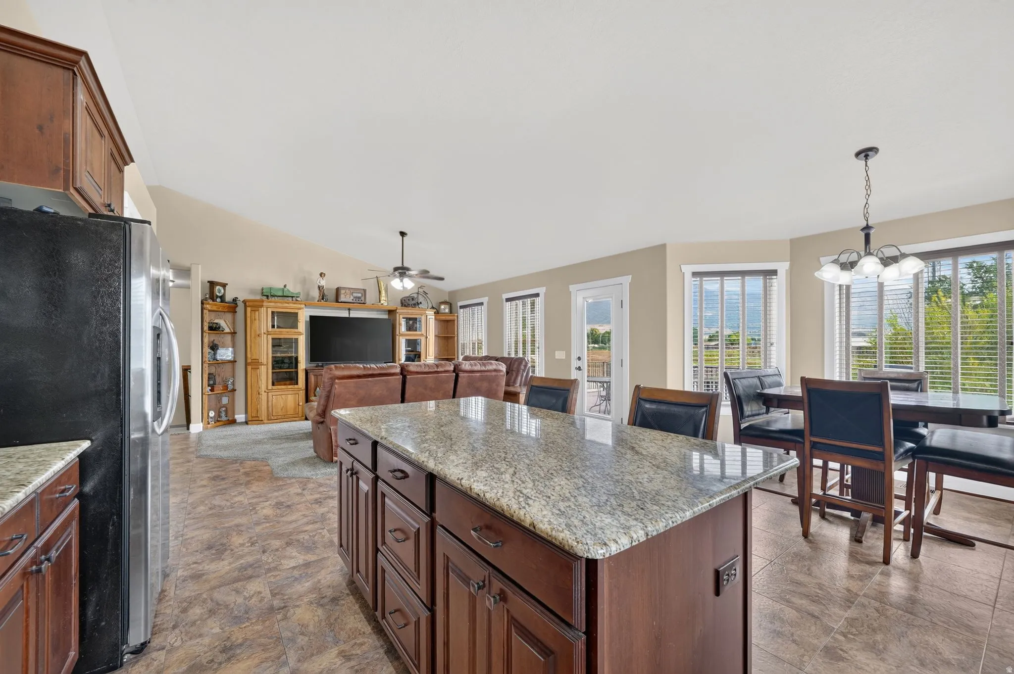Kitchen island featuring a granite countertop and rich wood cabinetry, with an open layout towards the living area and dining space