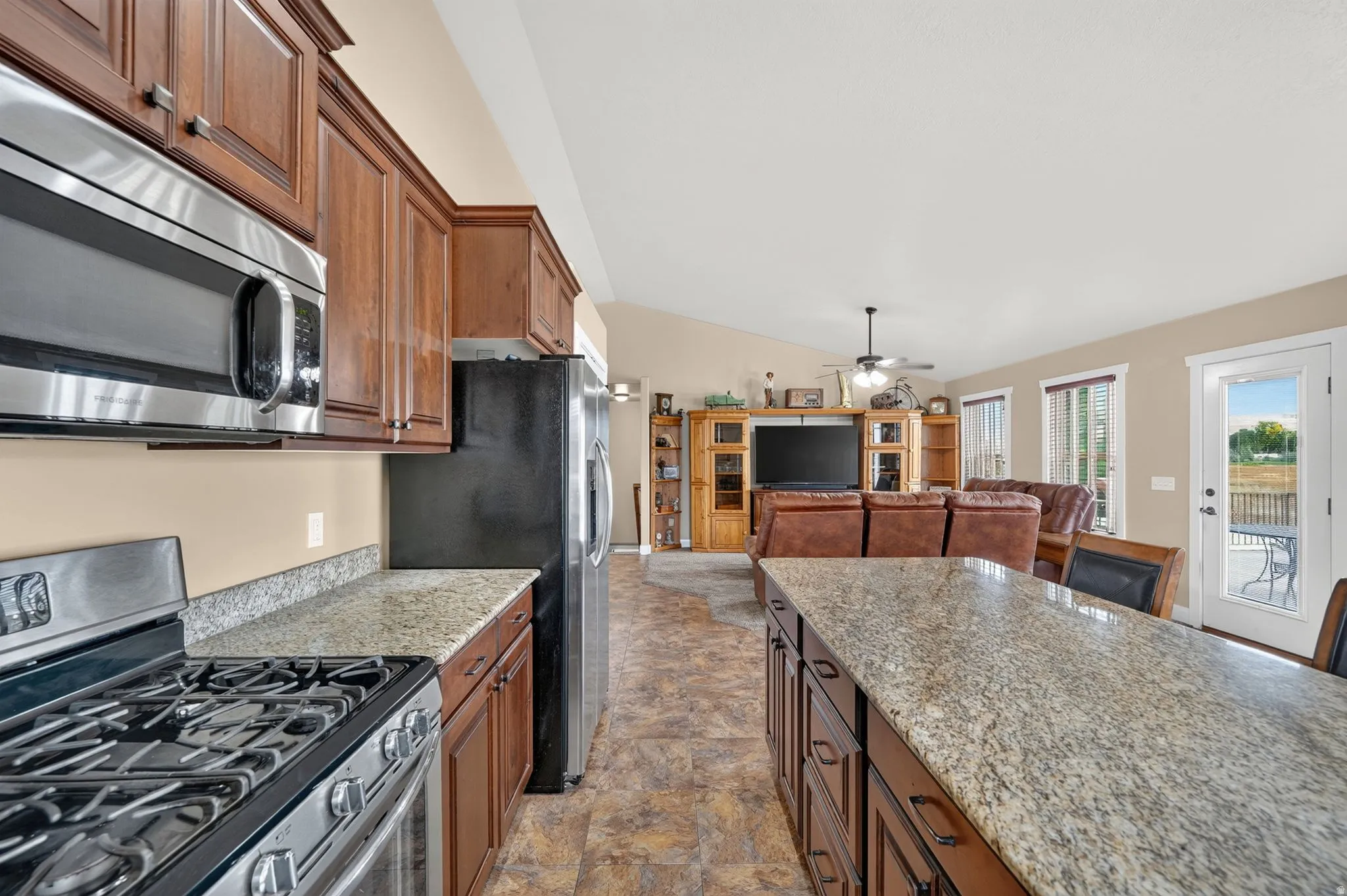 Kitchen featuring wood cabinetry, granite countertops, stainless steel appliances, and a gas range