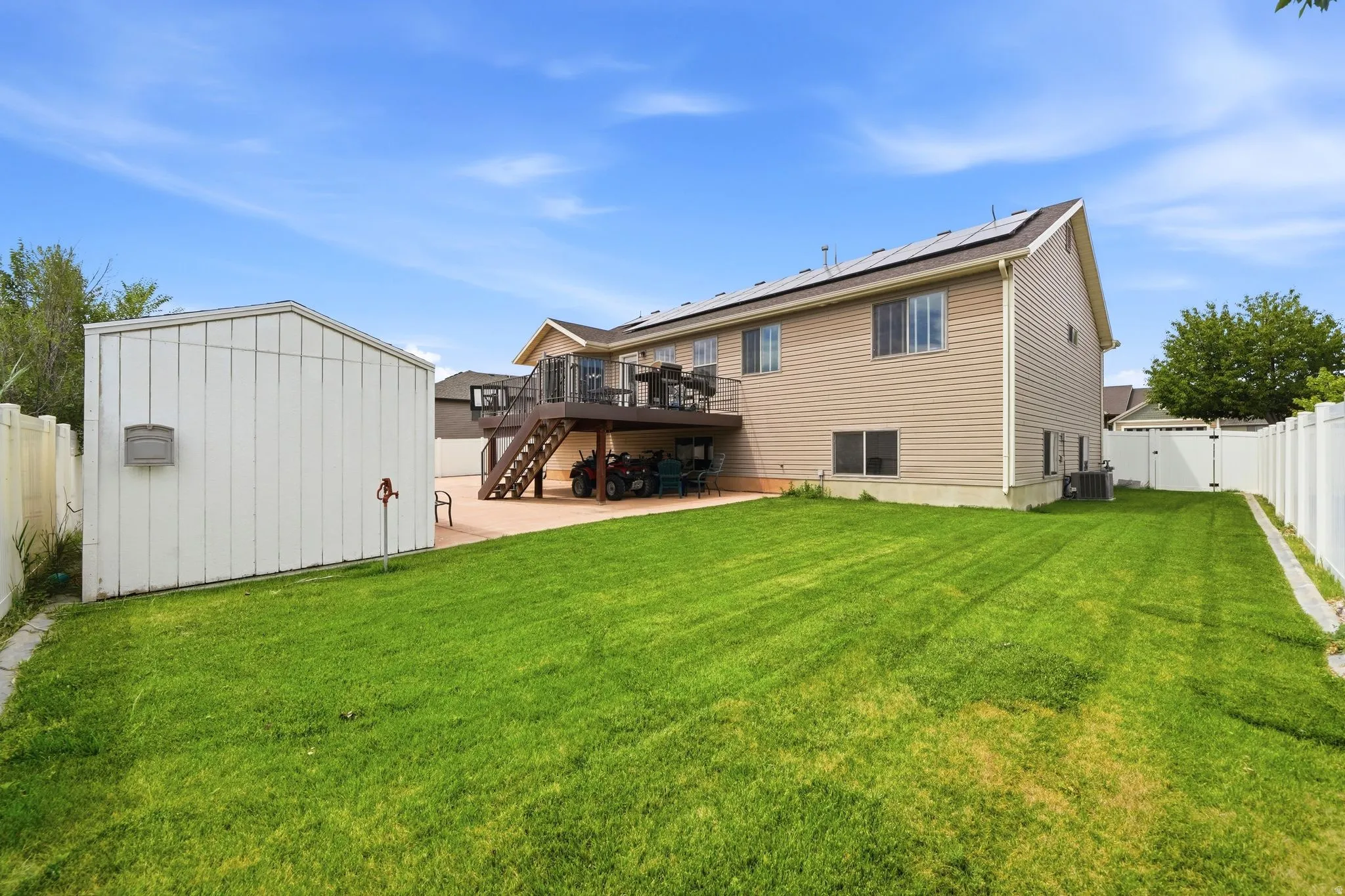 Expansive rear yard featuring a manicured lawn, a two-story deck, and a detached storage shed