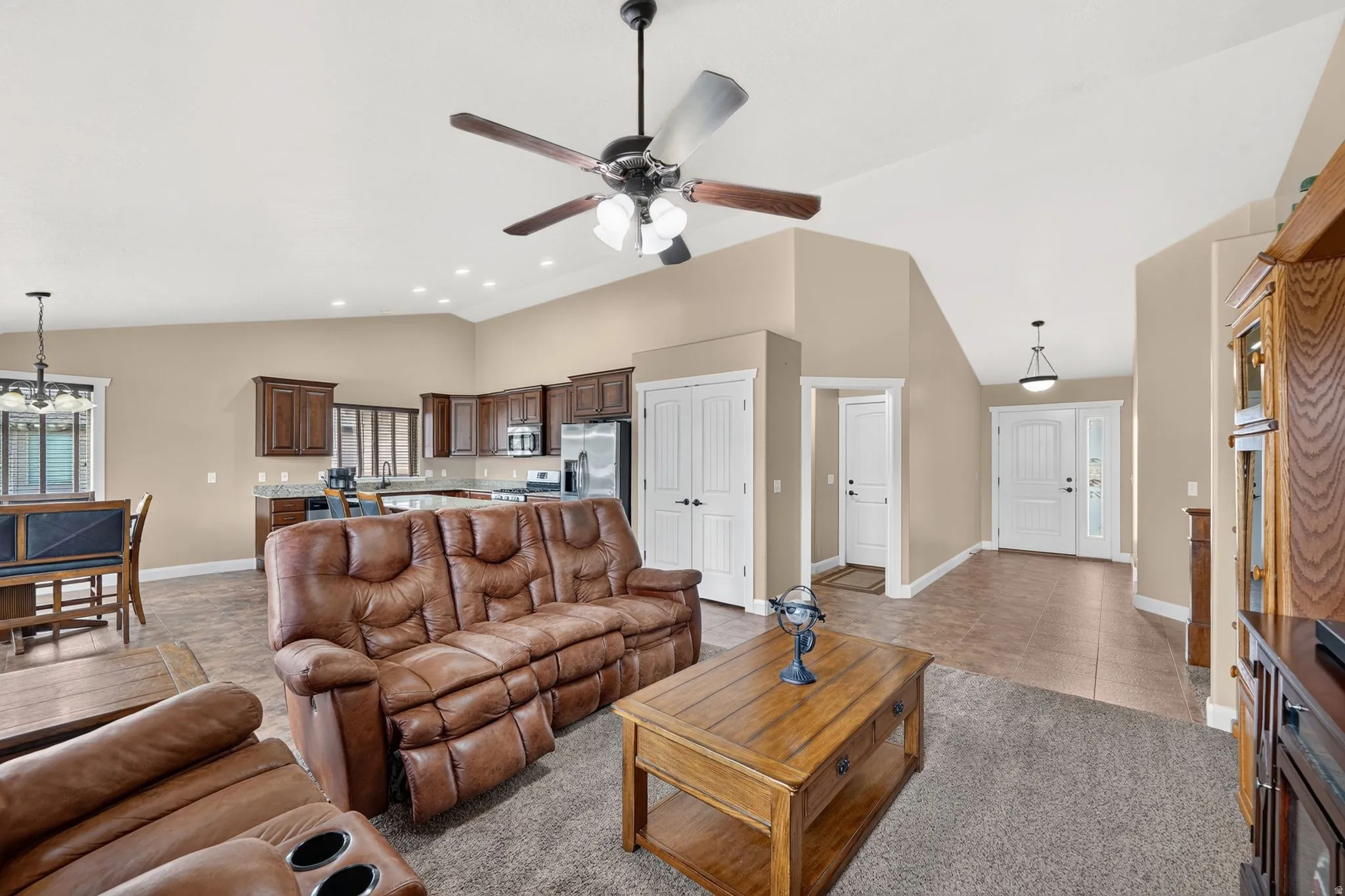 Open-concept living area featuring vaulted ceilings, recessed lighting, and a ceiling fan