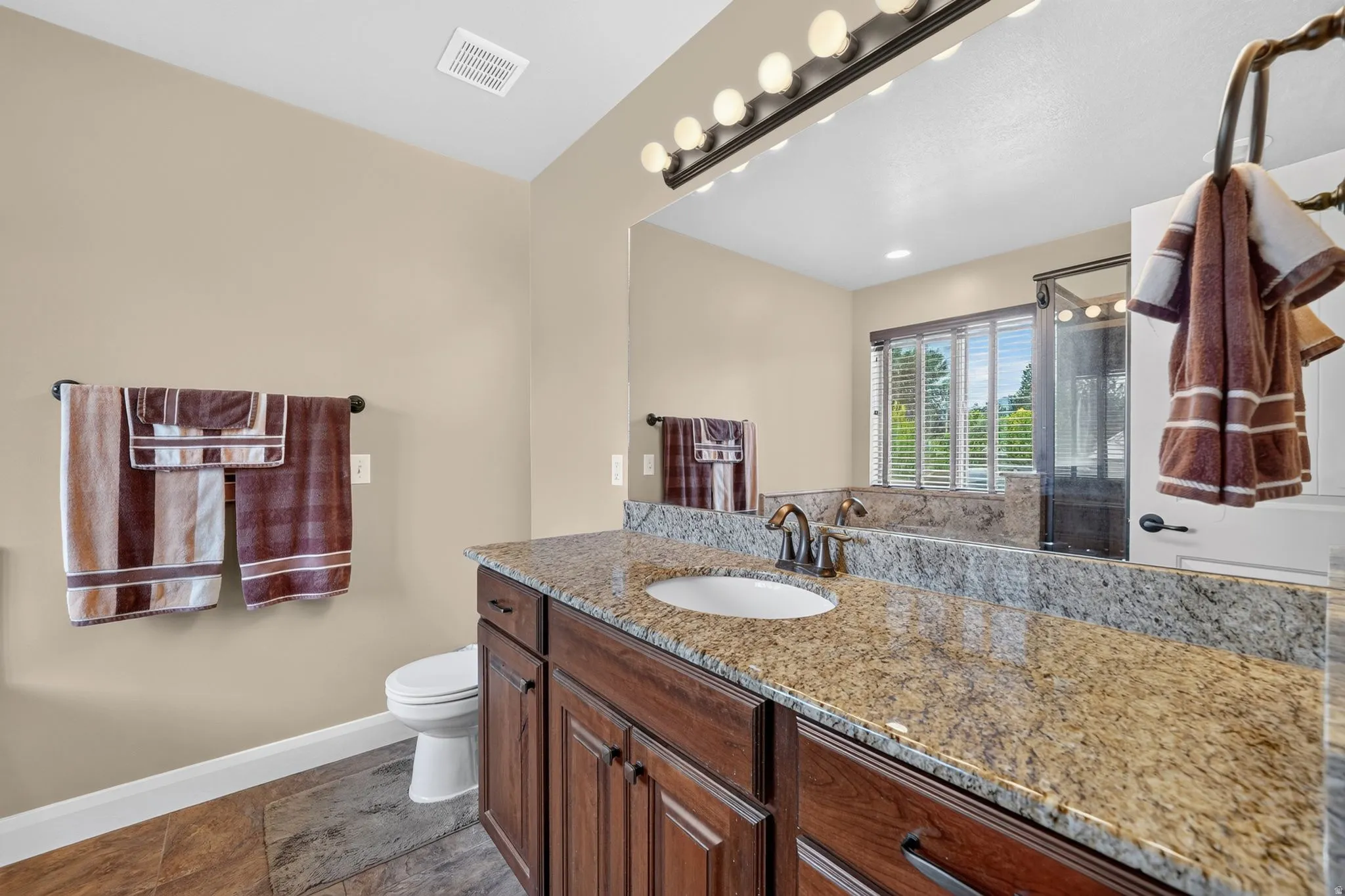 Bathroom vanity with a granite countertop, undermount sink, and dark wood cabinetry