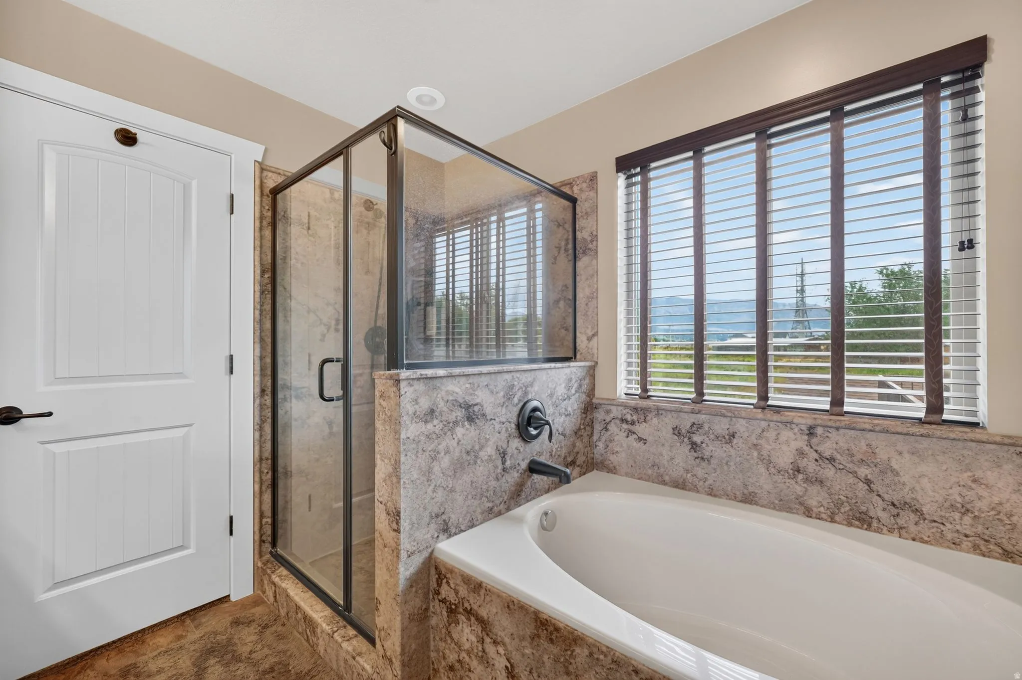 Built-in soaking tub and glass-enclosed shower with stone surround