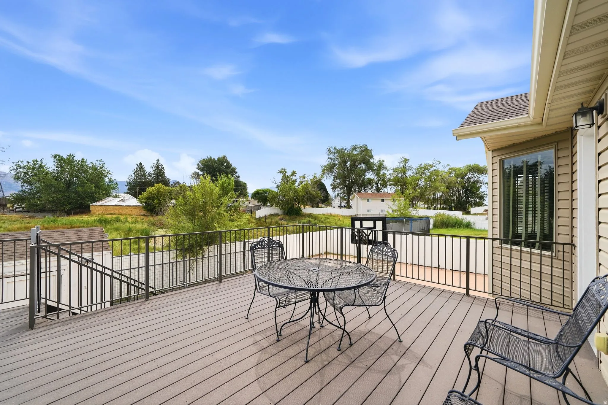 Spacious exterior deck featuring composite decking, black metal railing, and exterior wall lighting