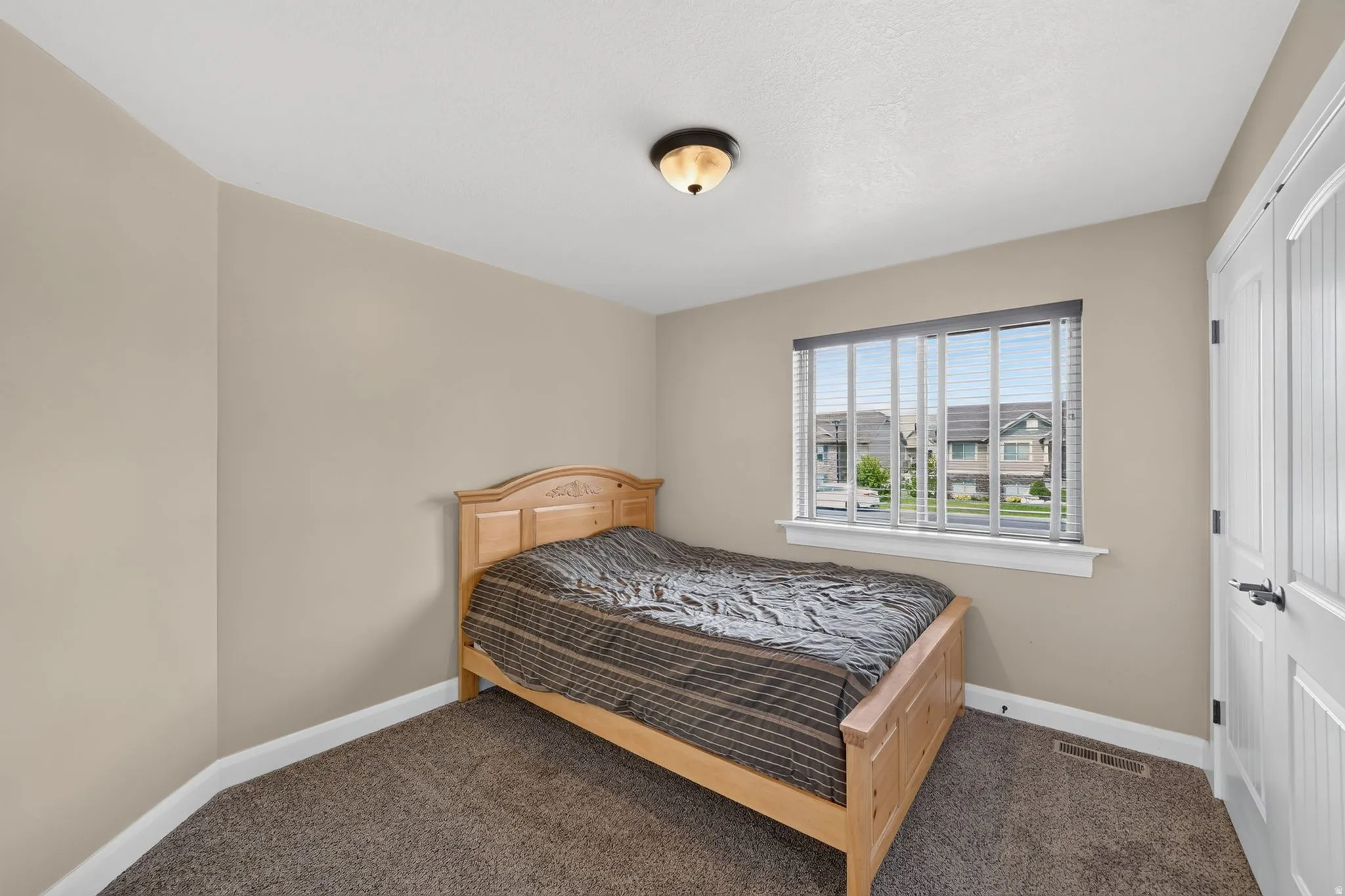 Carpeted room featuring neutral wall paint, a window with blinds, and white trim