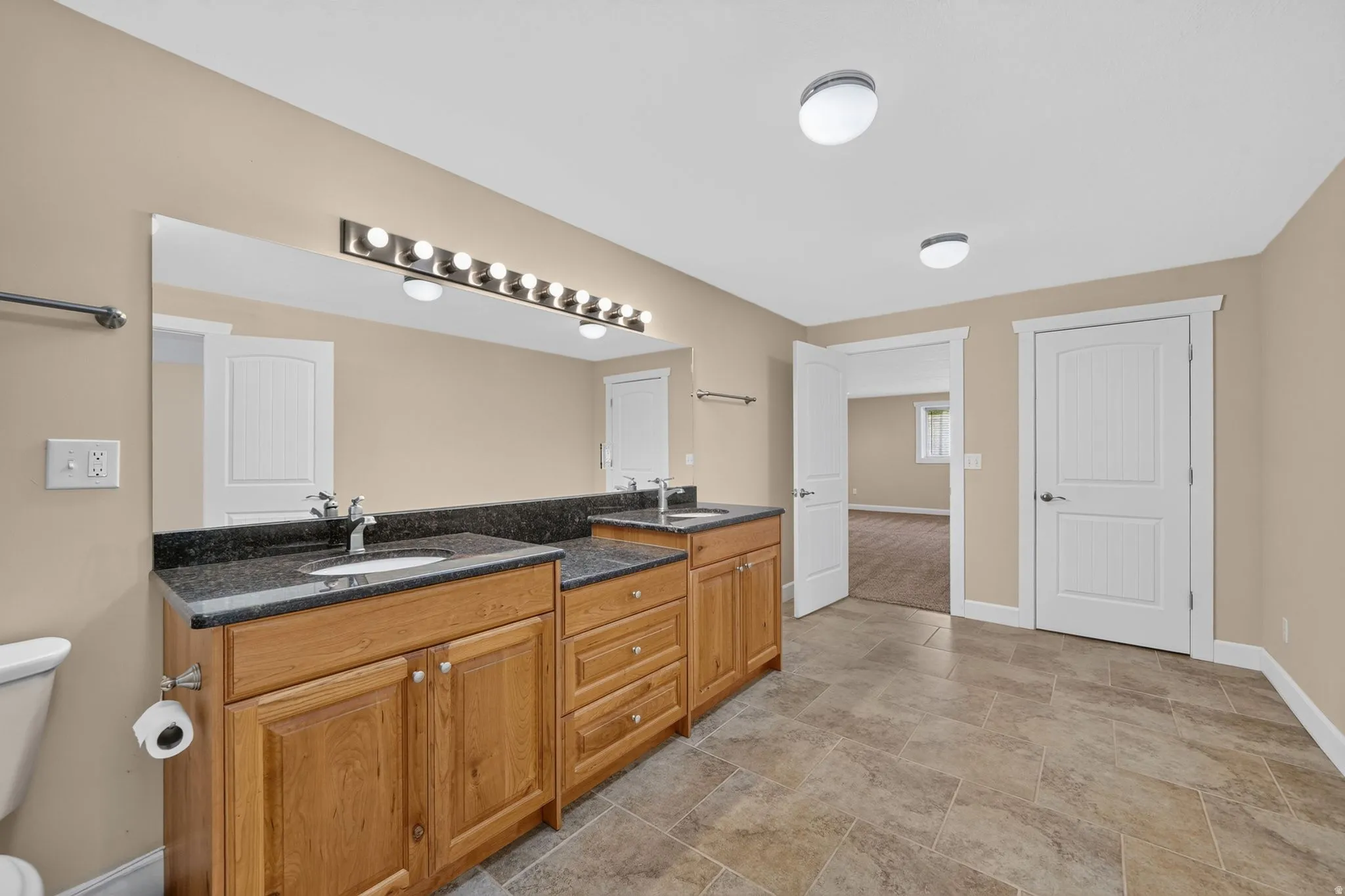 Double vanity with granite countertops, undermount sinks, and wood cabinetry