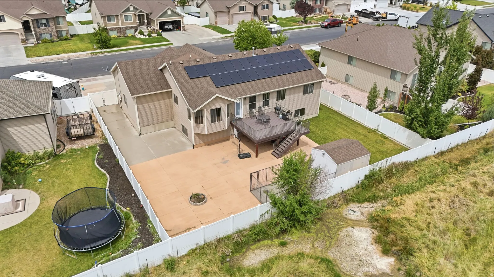 Two-story residence with a beige siding exterior and dark shingle roof featuring an attached garage and solar panels