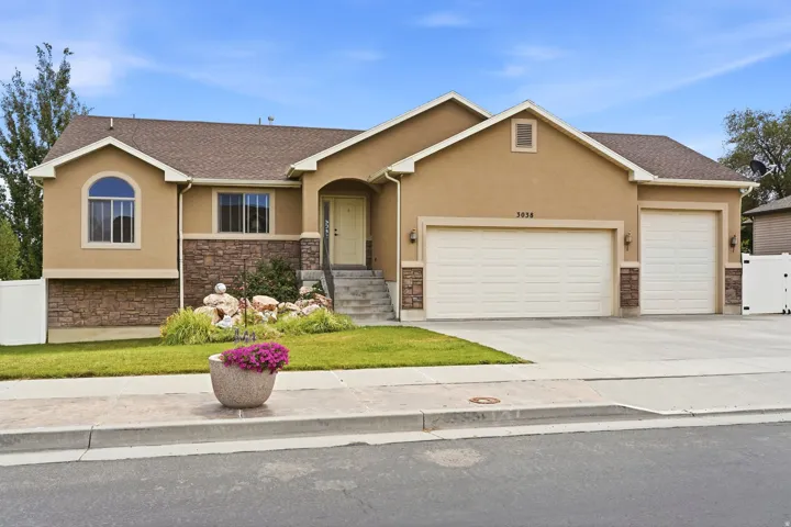 Stucco exterior with stone accenting, featuring an arched window and two-car garage