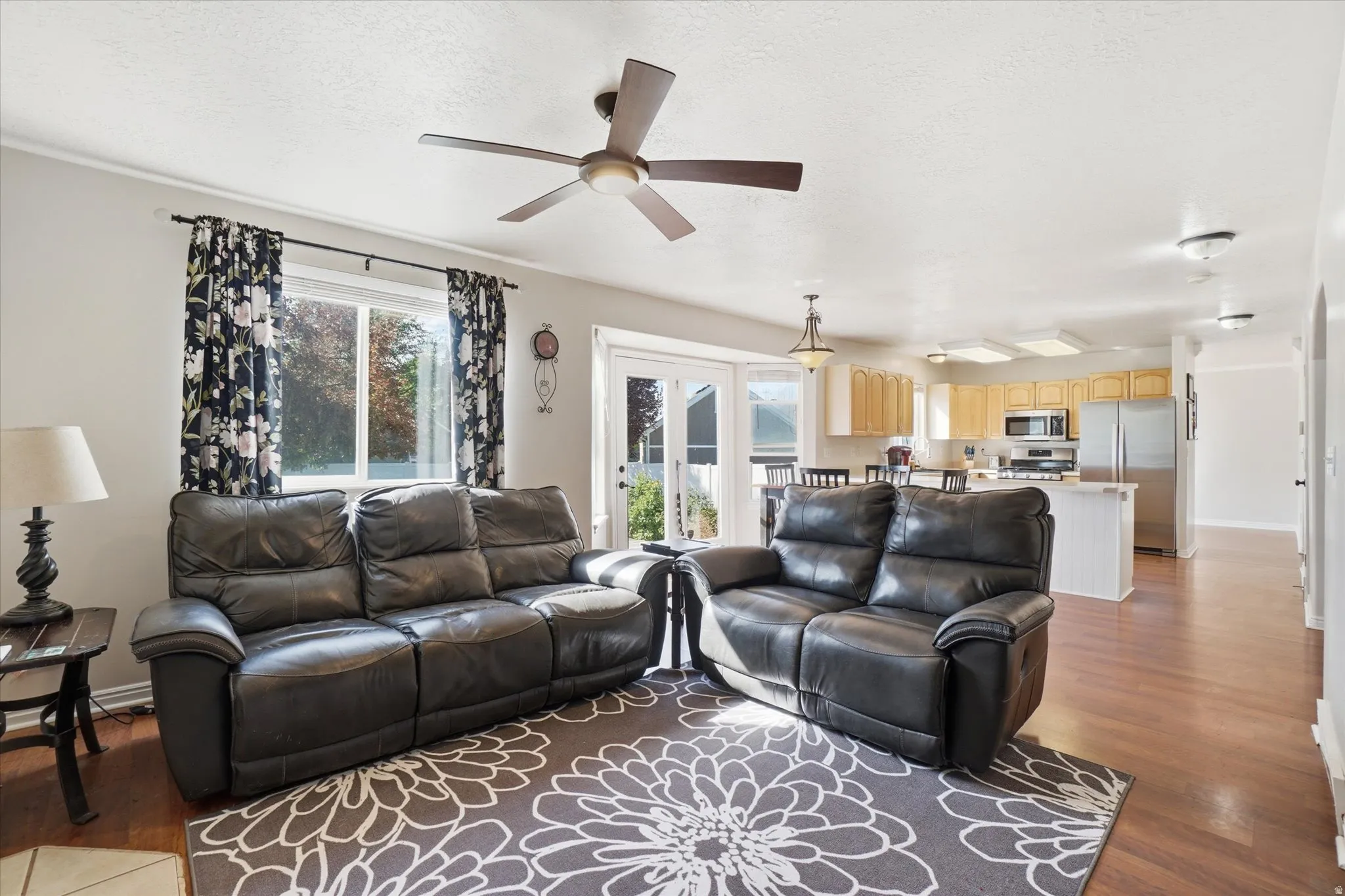Living room featuring dark wood-type flooring, plenty of natural light, ceiling fan, and a textured ceiling