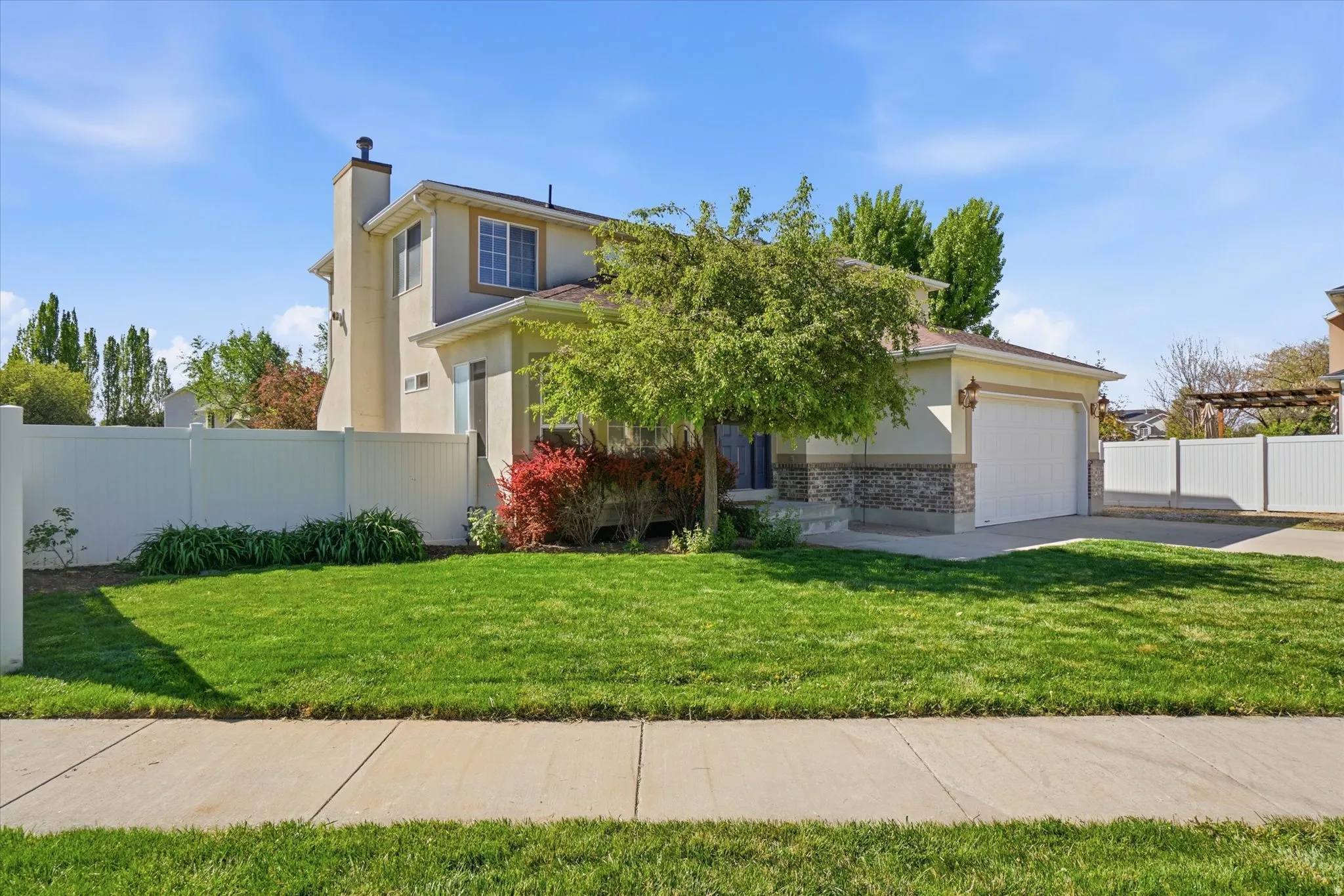 View of front of property with brick siding, stucco siding, a garage, driveway, and a chimney