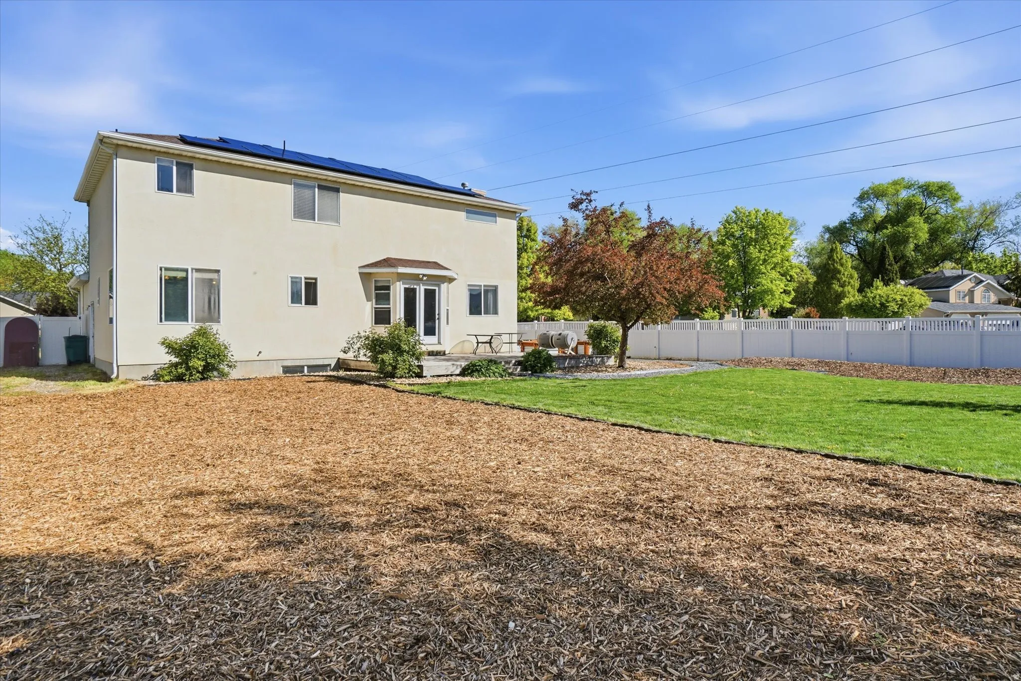 Back of property with solar panels, a patio area, a fenced backyard, and stucco siding