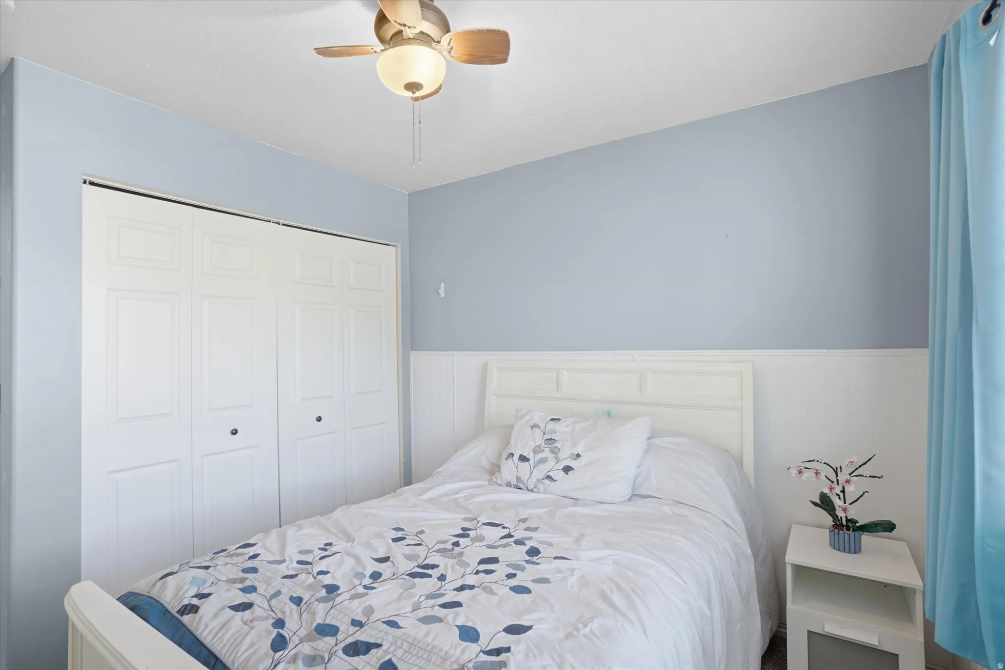 Bedroom with ceiling fan, a closet, and wainscoting