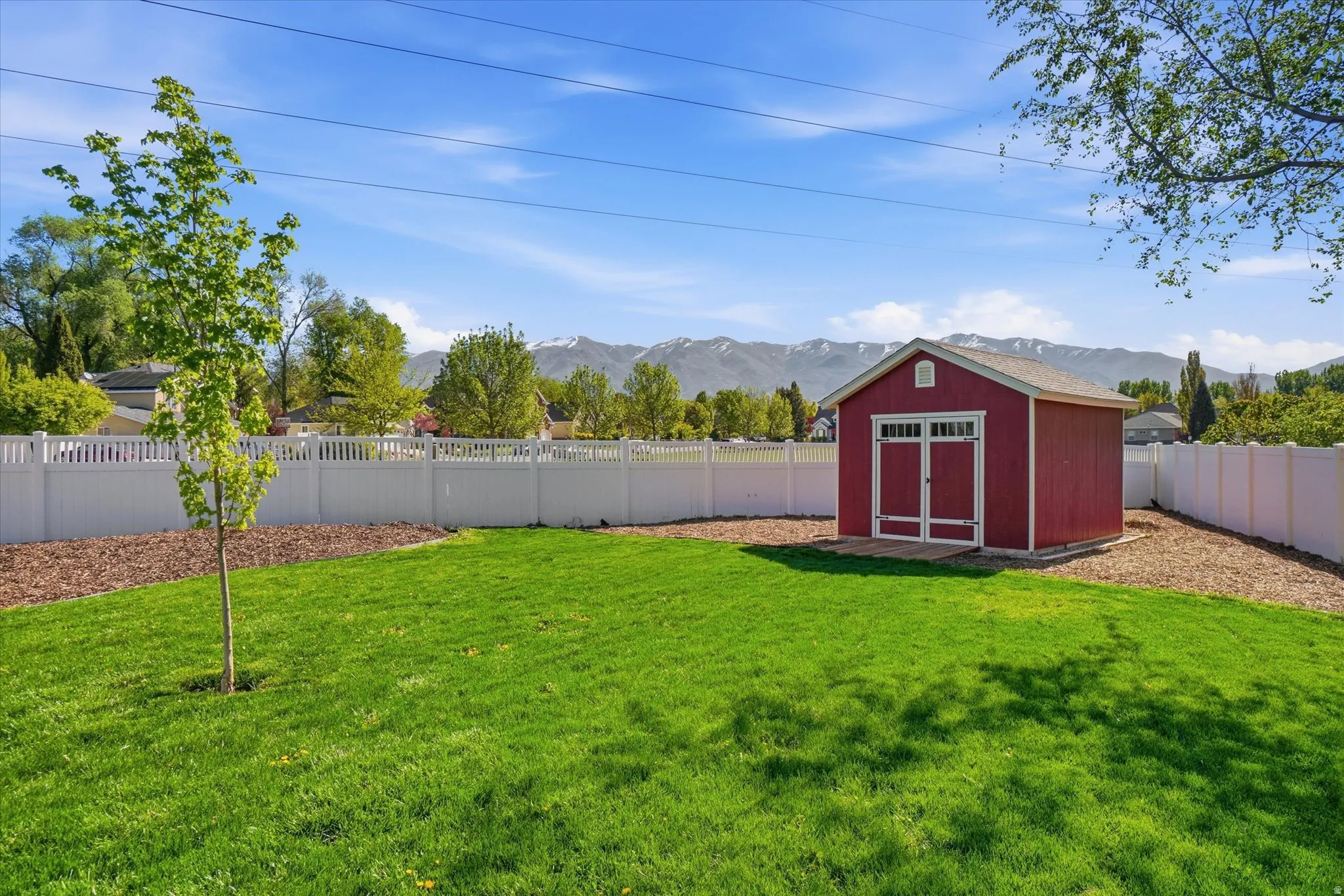 Fenced backyard featuring a shed and a mountain view