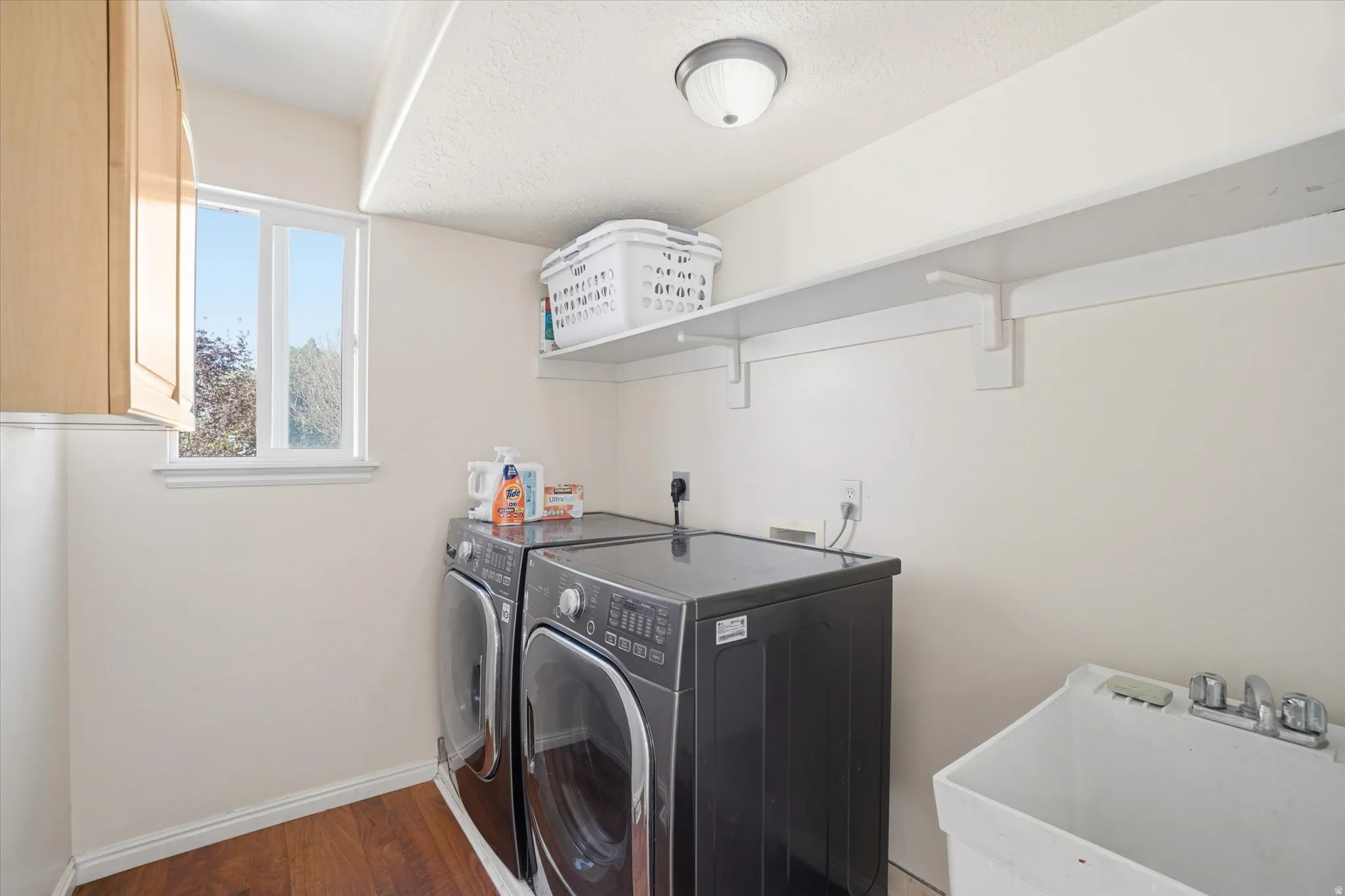 Laundry room featuring washing machine and clothes dryer, dark wood finished floors, and a textured ceiling