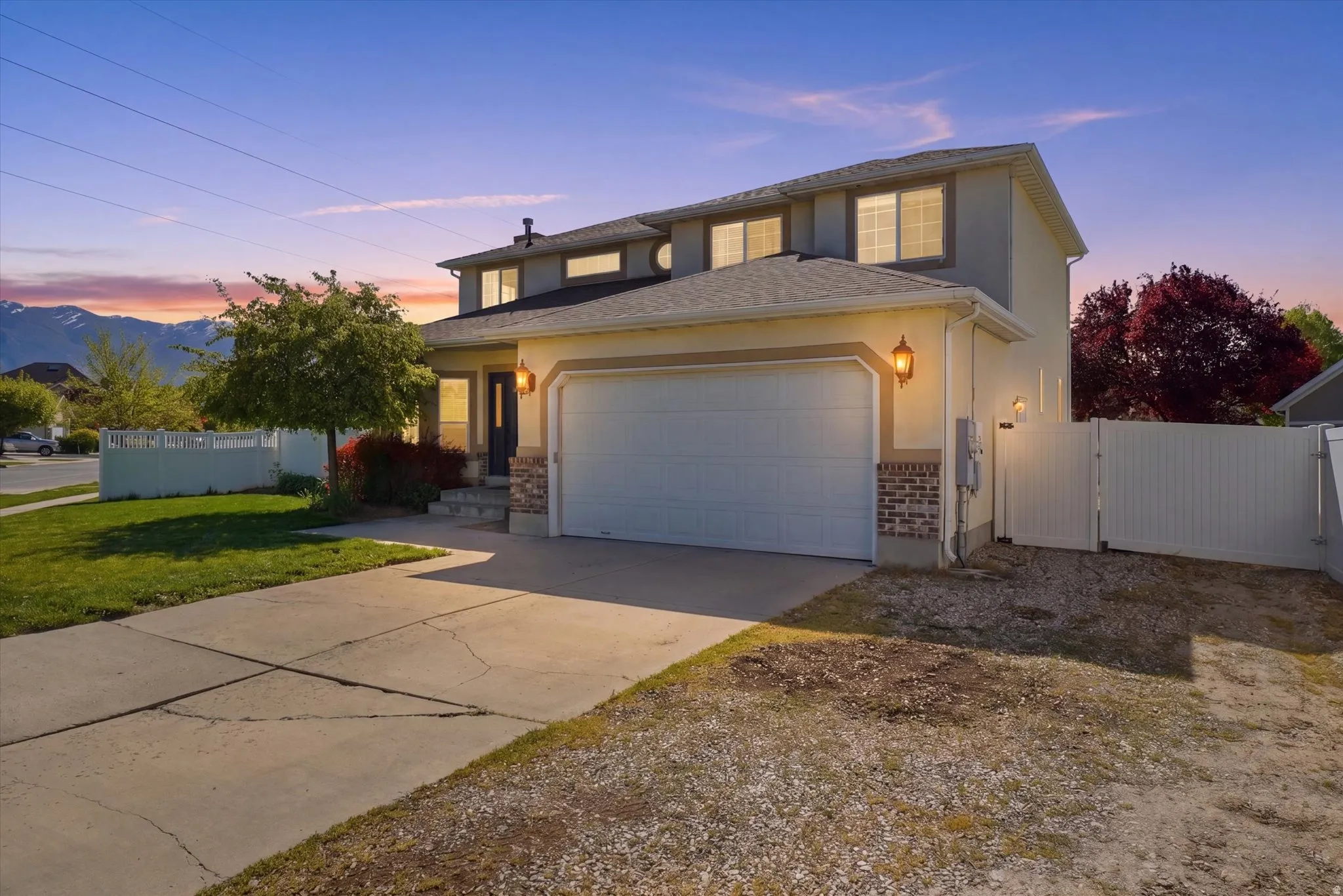 Traditional-style house with a gate, concrete driveway, a garage, stucco siding, and a mountain view