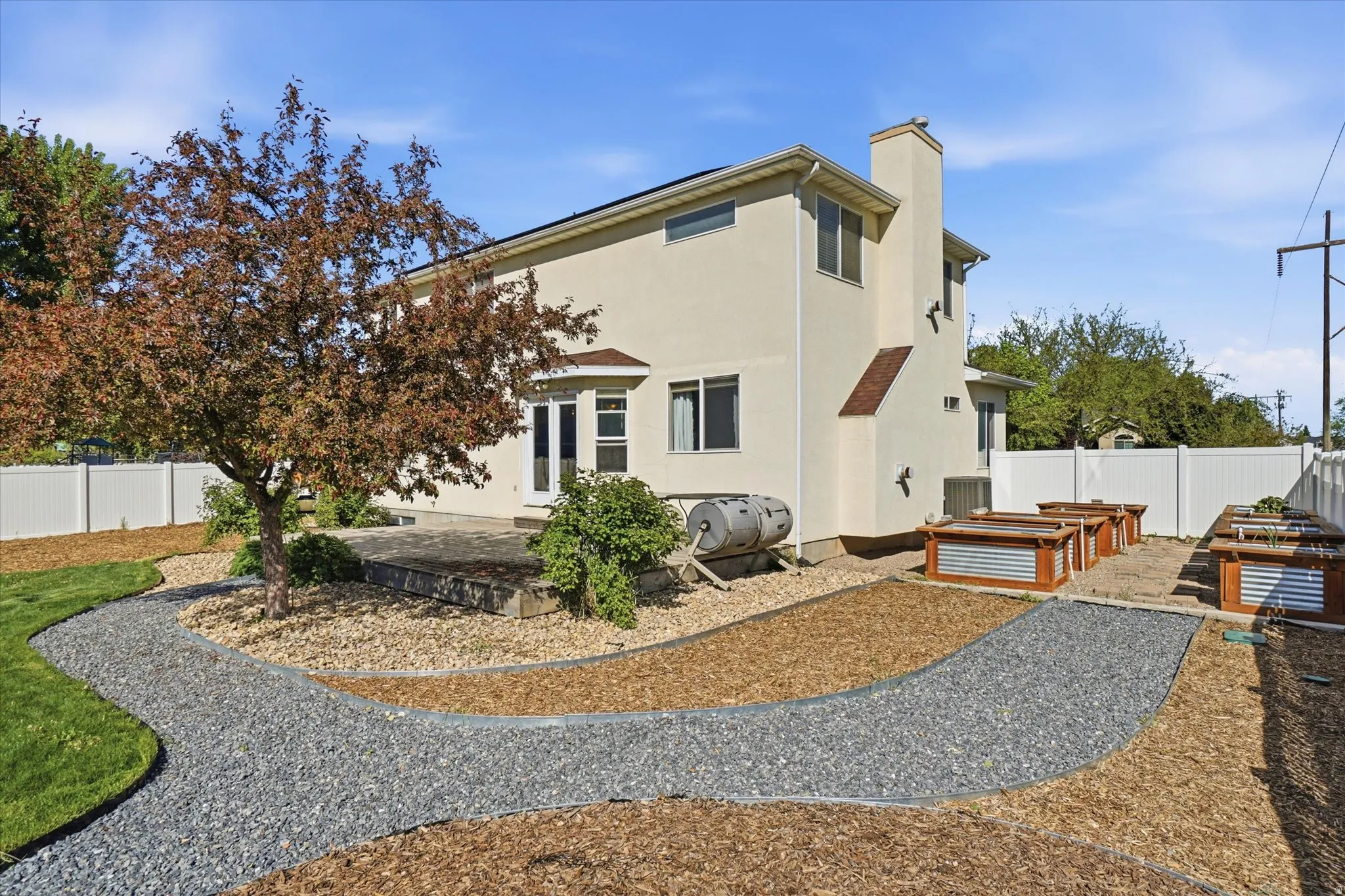 Back of house featuring a chimney, a garden, and stucco siding