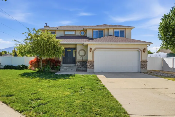 View of front of house with concrete driveway, an attached garage, brick siding, and stucco siding