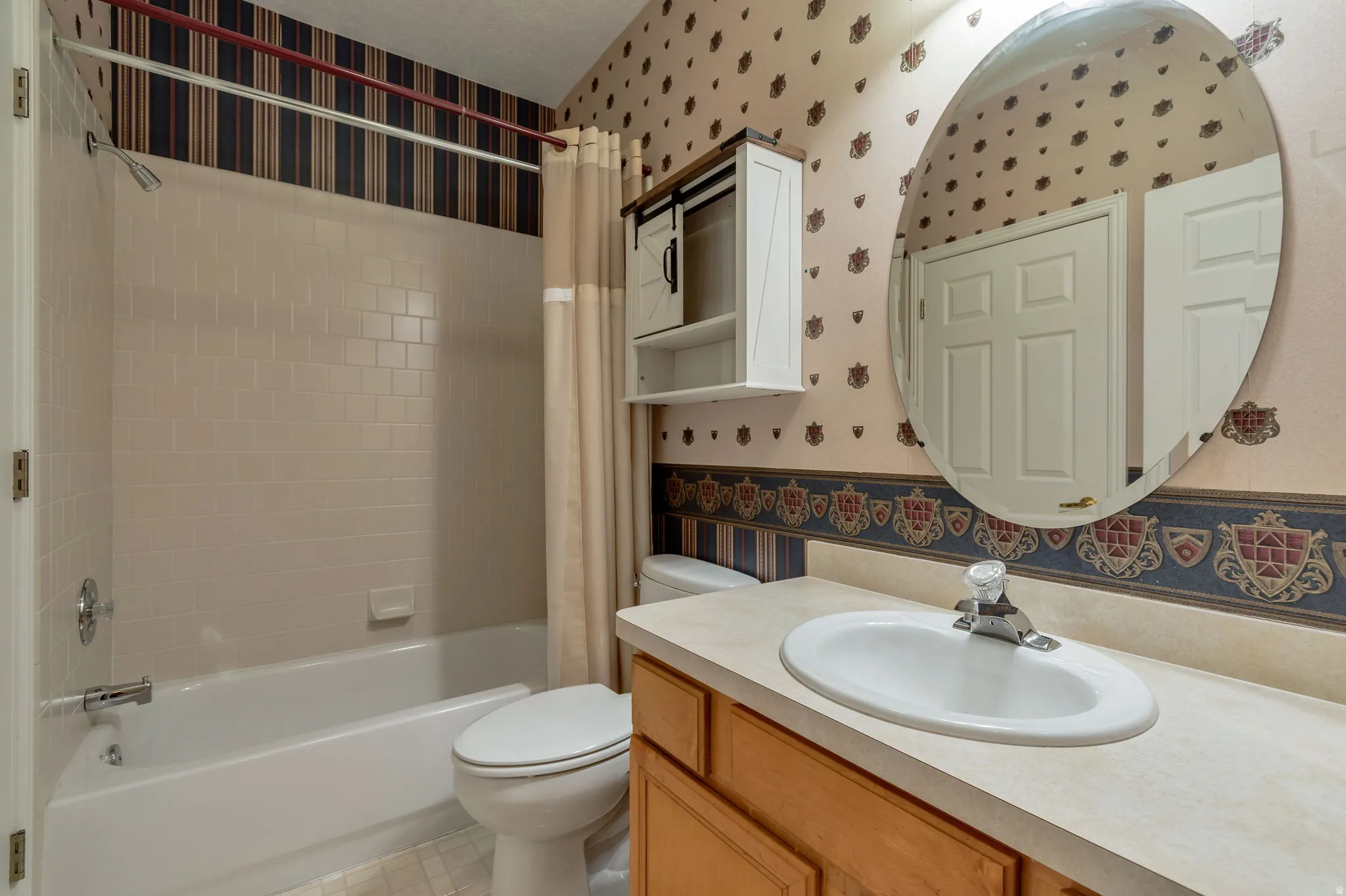 Full bathroom featuring wallpapered walls, vanity, and shower / tub combo with curtain