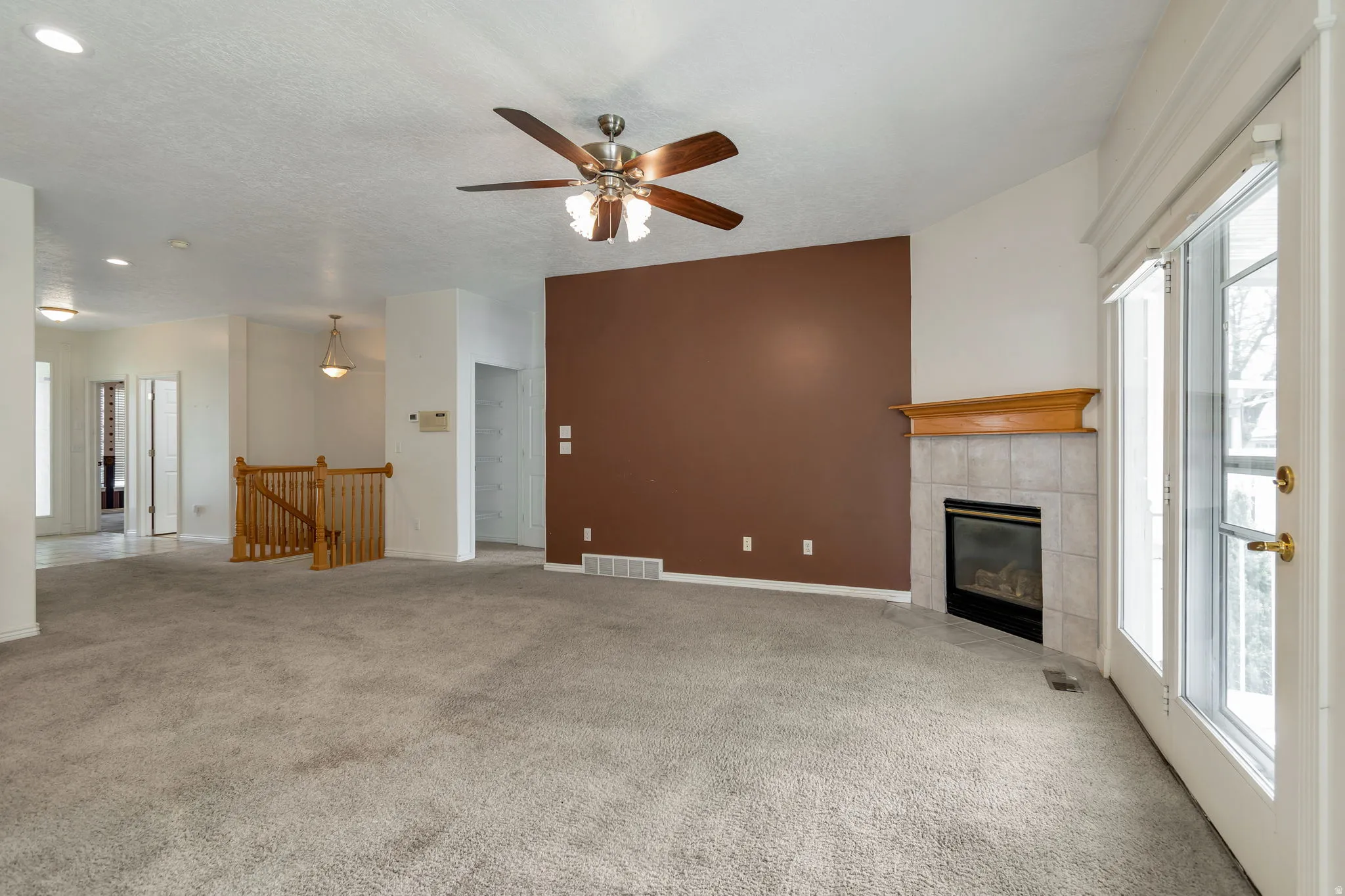 Unfurnished living room with a ceiling fan, light colored carpet, a fireplace, a textured ceiling, and recessed lighting