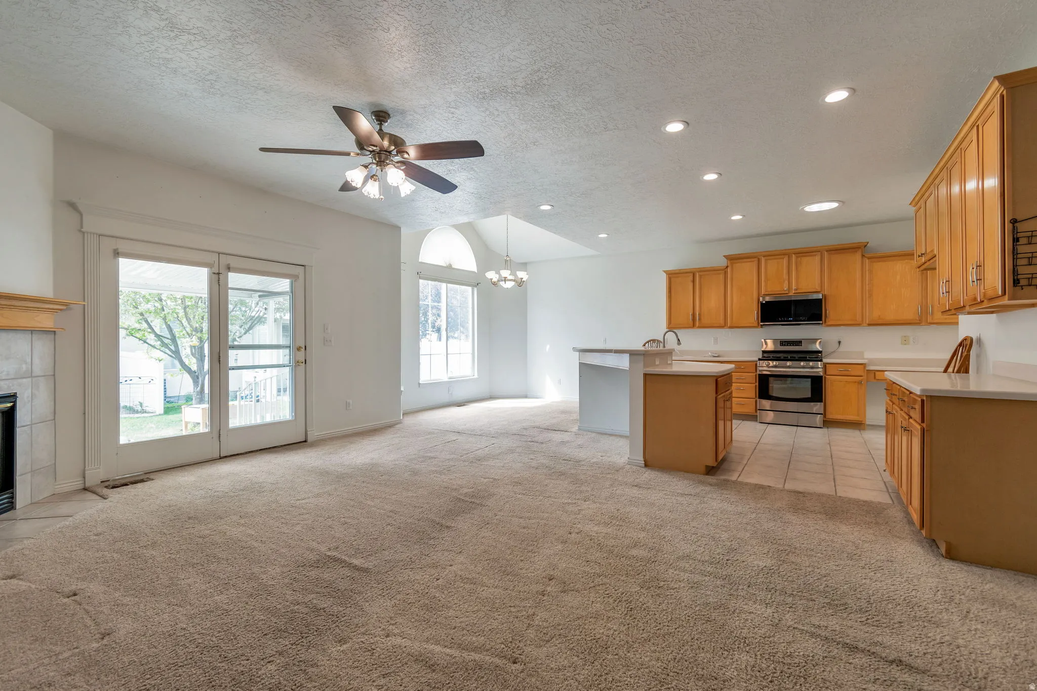 Kitchen with open floor plan, suspended lighting, light countertops, light carpet, and stainless steel appliances