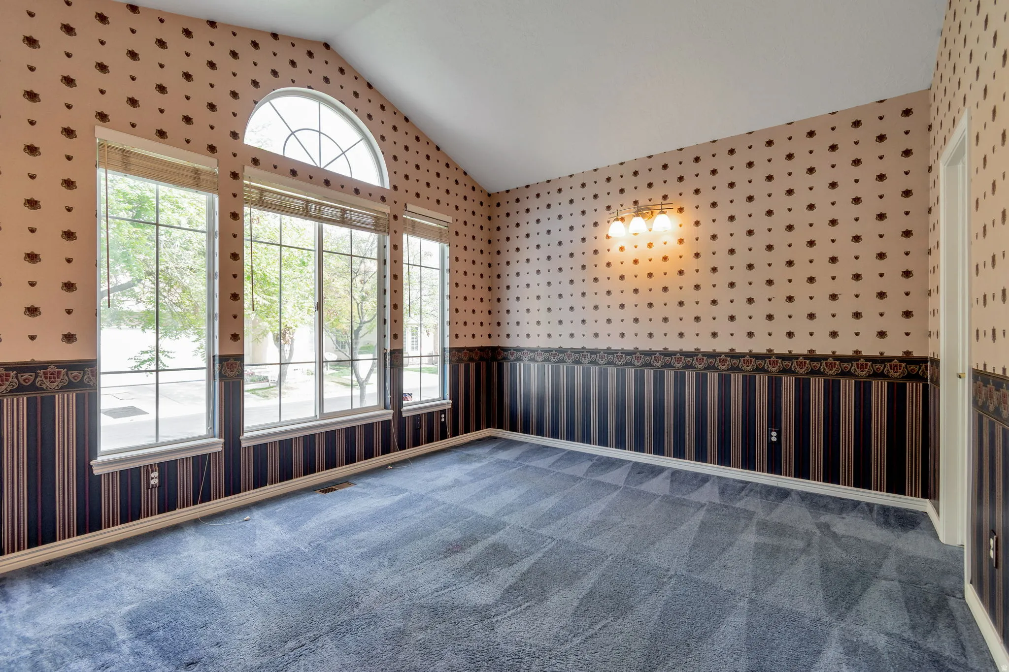 Unfurnished room with wallpapered walls, wainscoting, and carpet flooring