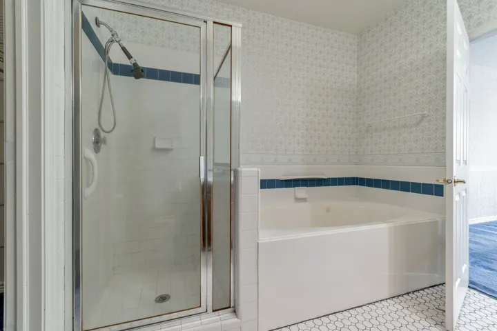 Full bathroom with wallpapered walls, a bath, a stall shower, and light tile patterned floors