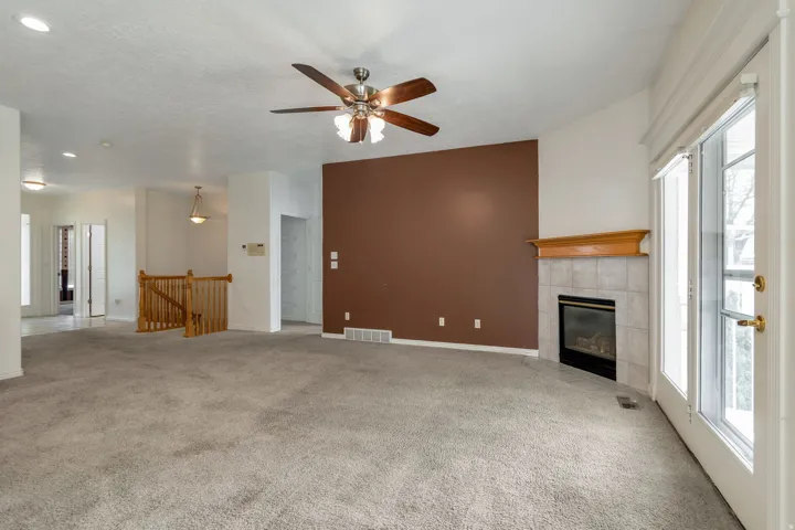 Unfurnished living room with a ceiling fan, light colored carpet, a fireplace, a textured ceiling, and recessed lighting