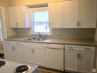 Kitchen featuring white appliances, white cabinetry, and light countertops
